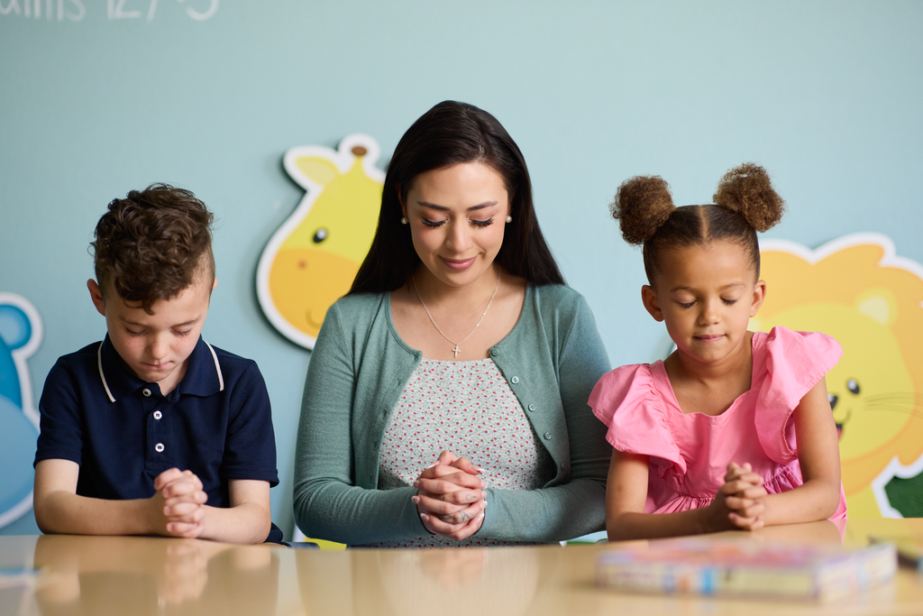 A teacher praying with her students
